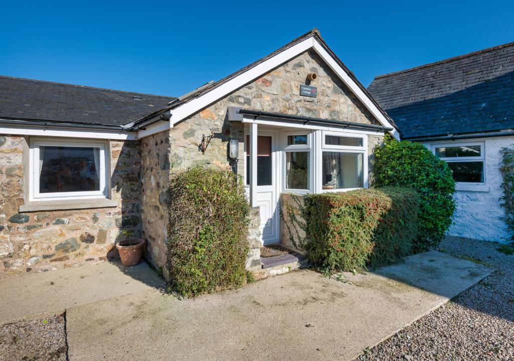 a stone house with a white door at Camellia Cottage in Llanbedrog