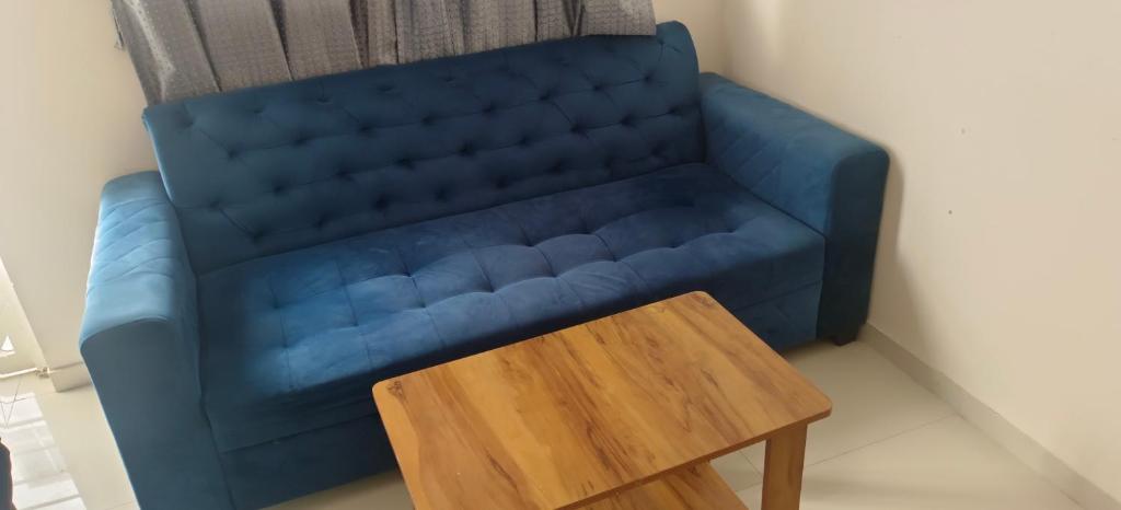 Akshra residency 1 bhk في هنجاودي: أريكة زرقاء في غرفة مع طاولة خشبية