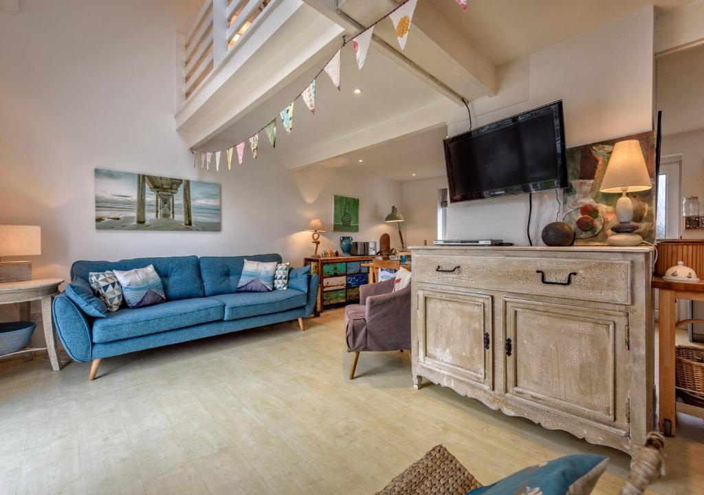 a living room with a blue couch and a tv at St Tudwals View in Abersoch