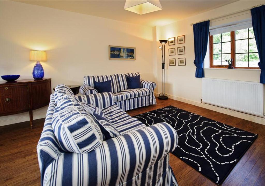 a living room with two striped couches and a rug at Y Betws in Abersoch