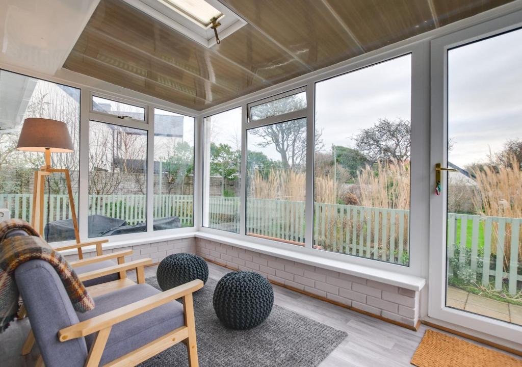 a screened in porch with windows and a couch at Murmur Y Llanw in Port-Eynon