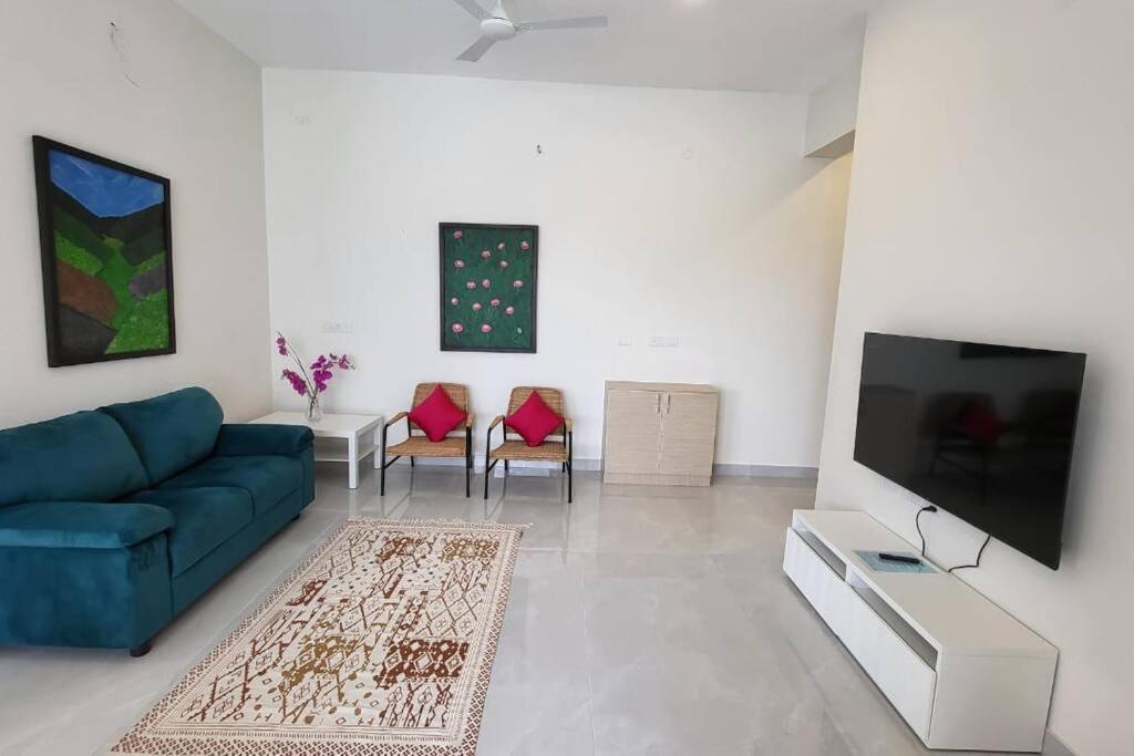 a living room with a blue couch and a flat screen tv at Lucky Charm 2BHK Apartment - Muttukadu ECR in Chennai