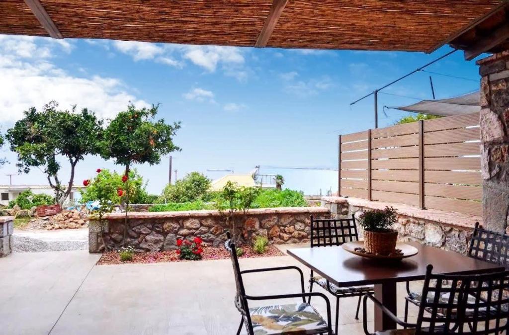 a patio with a table and chairs and a stone wall at Verga Paradise Nest - A Blissful Hideout in Almirón