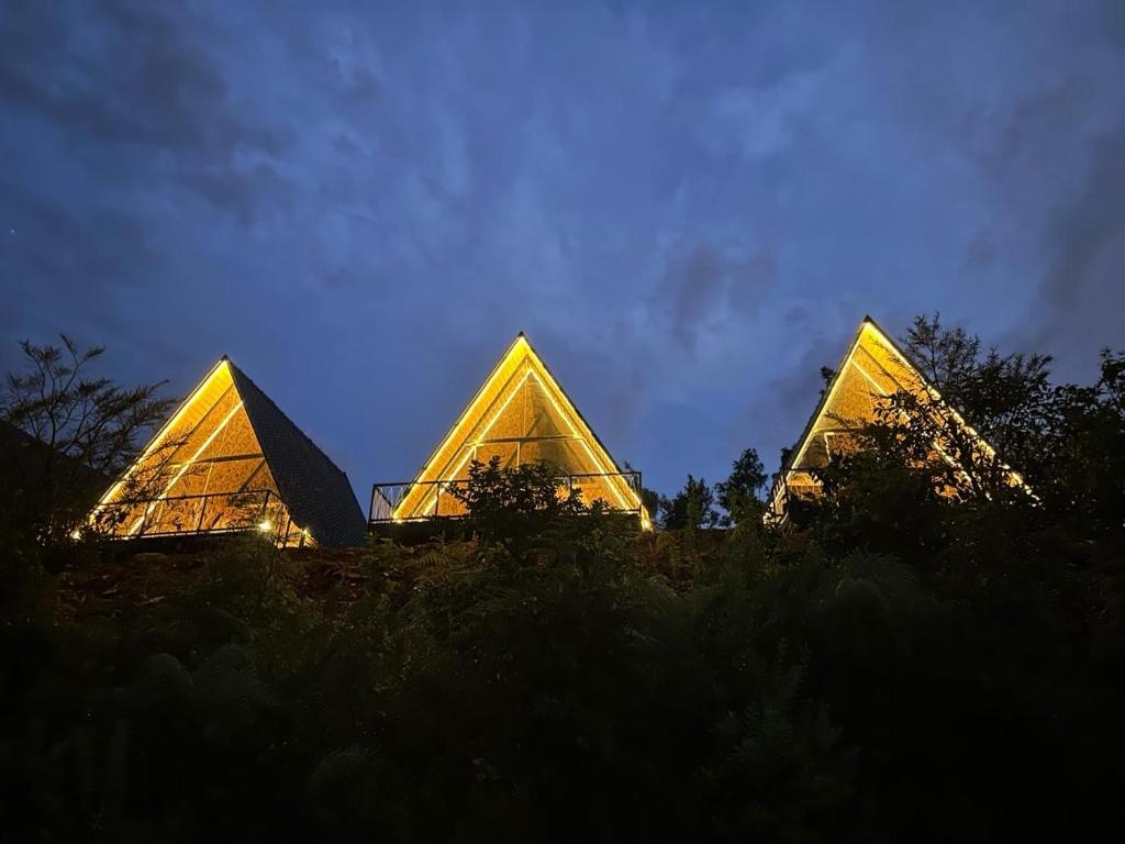 three pyramids sitting on top of a hill at night at Ikshana Cottages in Kalasa