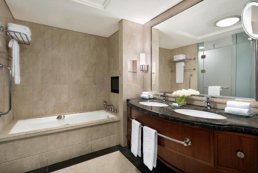 a bathroom with two sinks and a tub and a mirror at Shangri-La Jakarta in Jakarta