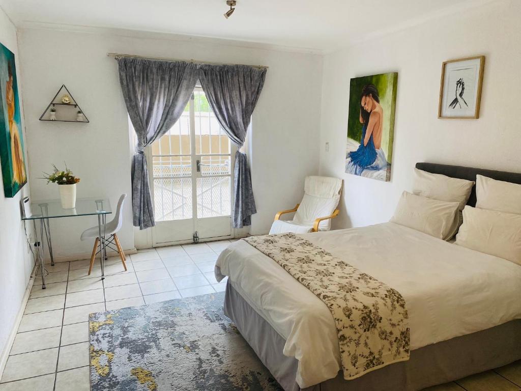 a bedroom with a bed and a table and a window at Hatfield, Grosvenor Private apartment. in Pretoria