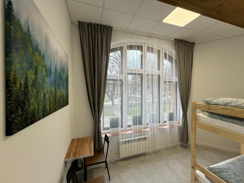 a bedroom with a window and a painting on the wall at Green Hostel Katowice 24h - Parking in Katowice