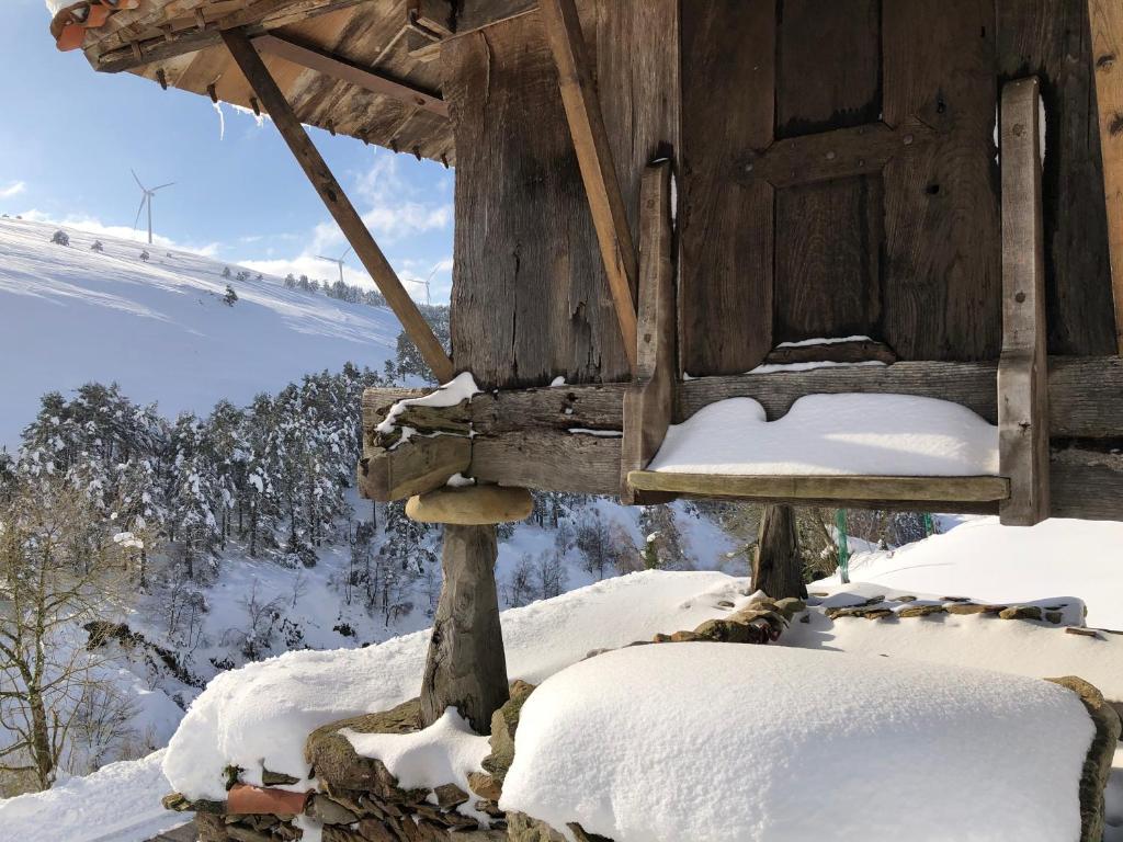 Cabaña de madera con nieve en el suelo en Ca Manín, en Tineo