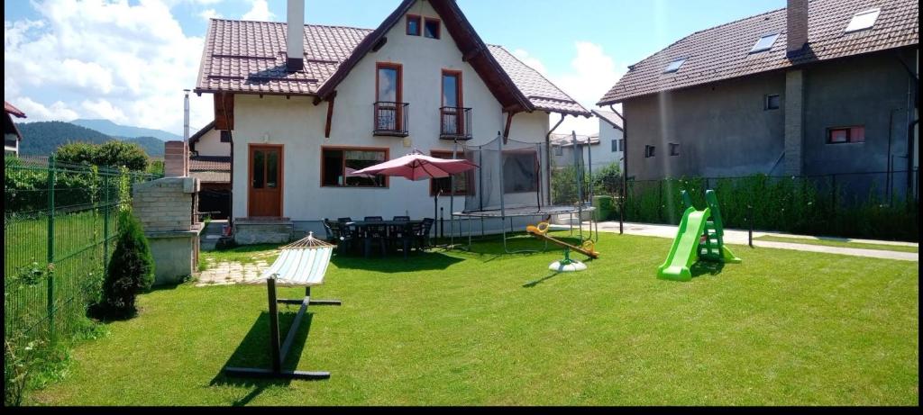 einen Hof mit einem Spielplatz mit einem Haus in der Unterkunft Vila Decebal in Râșnov