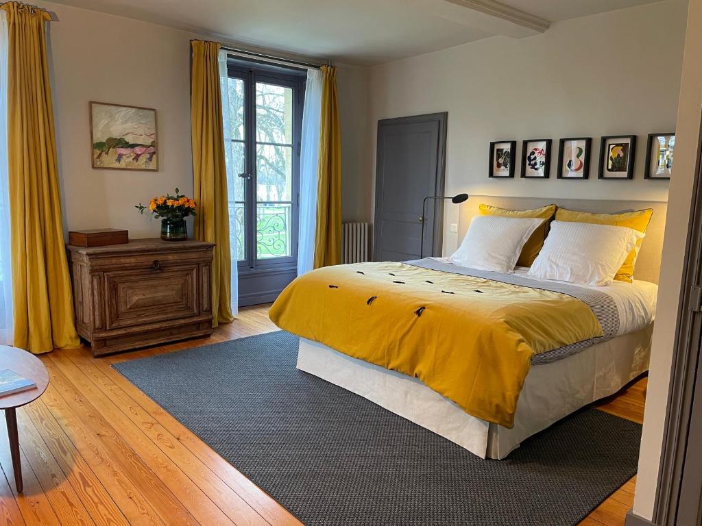 um quarto com uma cama grande e um cobertor amarelo em Le Mûrier de Bayeux em Bayeux