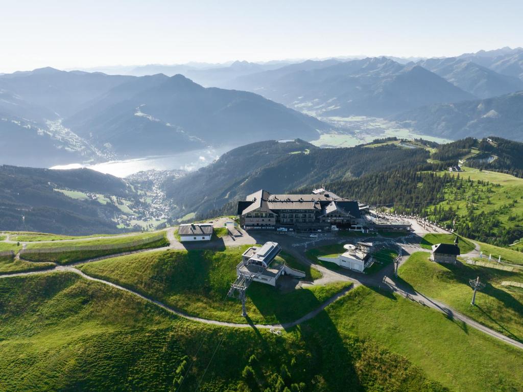 una vista aerea di una casa su una collina con montagne di Berghotel Schmittenhöhe - 2000m a Zell am See