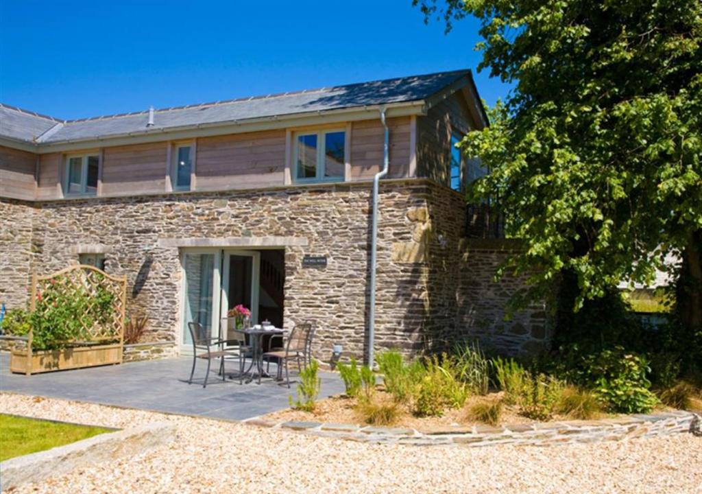 a stone house with a patio and a table at The Well House Trevisquite in Saint Tudy