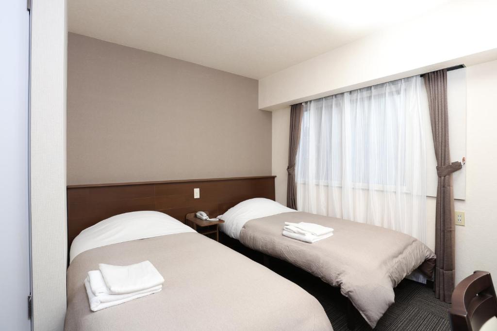 Habitación de hotel con 2 camas y ventana en Sapporo Oriental Hotel, en Sapporo