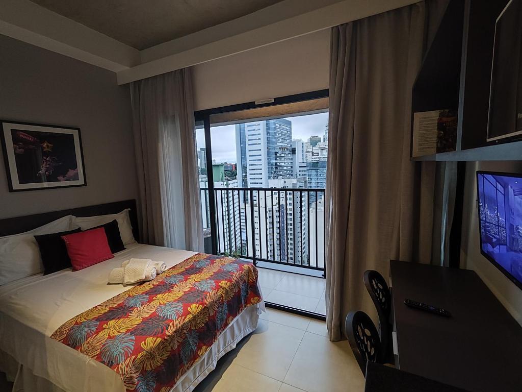 a bedroom with a bed and a balcony with a television at Studio de cobertura perto da av. Paulista in Sao Paulo
