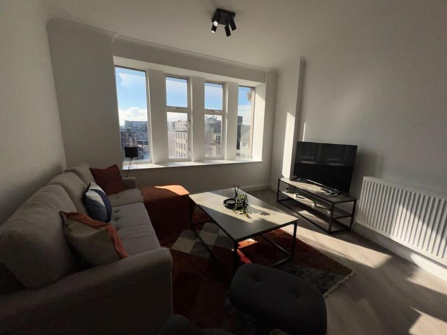 City View Apartment في ديربي: غرفة معيشة مع أريكة وطاولة وتلفزيون