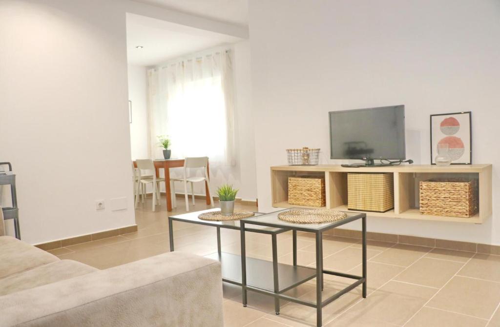 Una sala de estar con un televisor y una mesa. en Apartamento Goya, en Conil de la Frontera