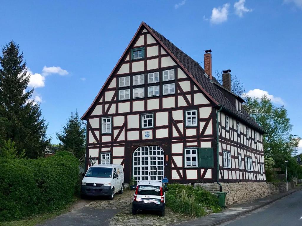 un bâtiment avec deux voitures garées devant lui dans l'établissement Ferienwohnung Gottsbüren, à Trendelburg