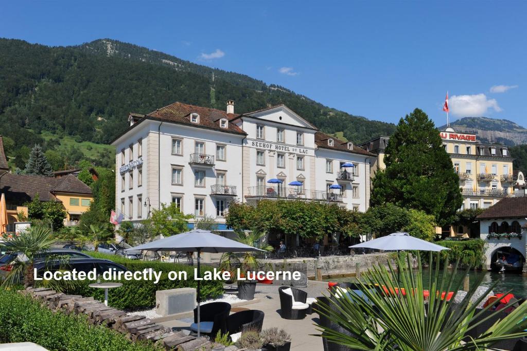 ein Hotel mit Tischen und Sonnenschirmen vor einem Gebäude in der Unterkunft Seehof Hotel Du Lac in Weggis