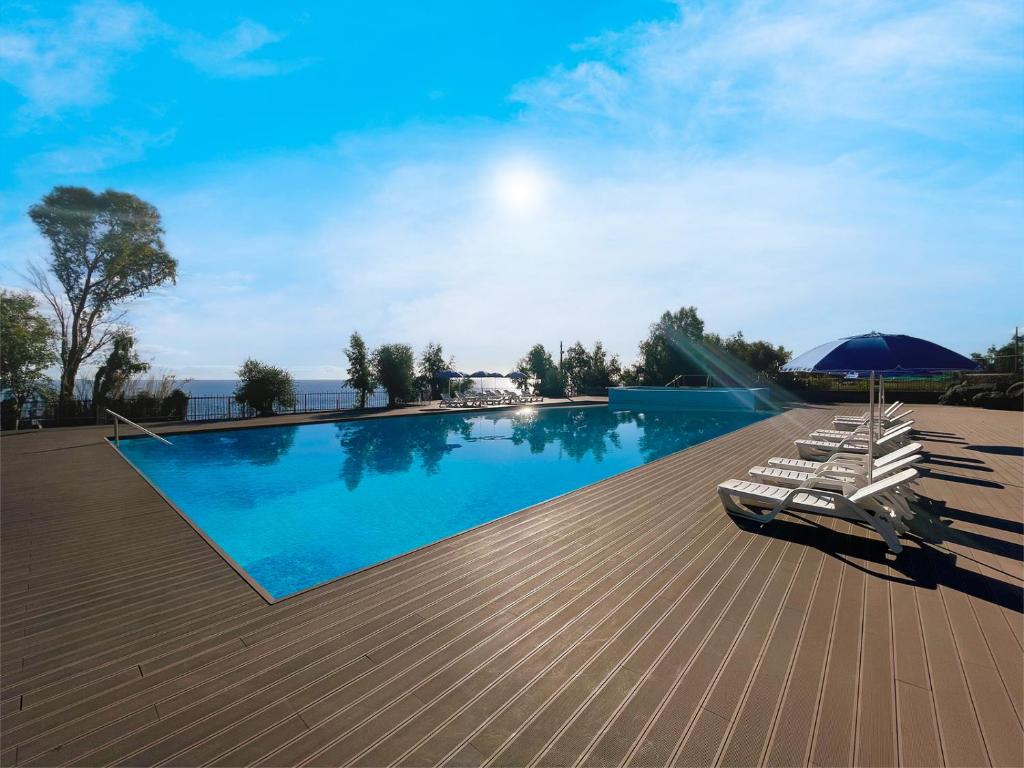 una piscina con sedie a sdraio e ombrellone di Il Pampaleone Glamping and Resort ad Acireale