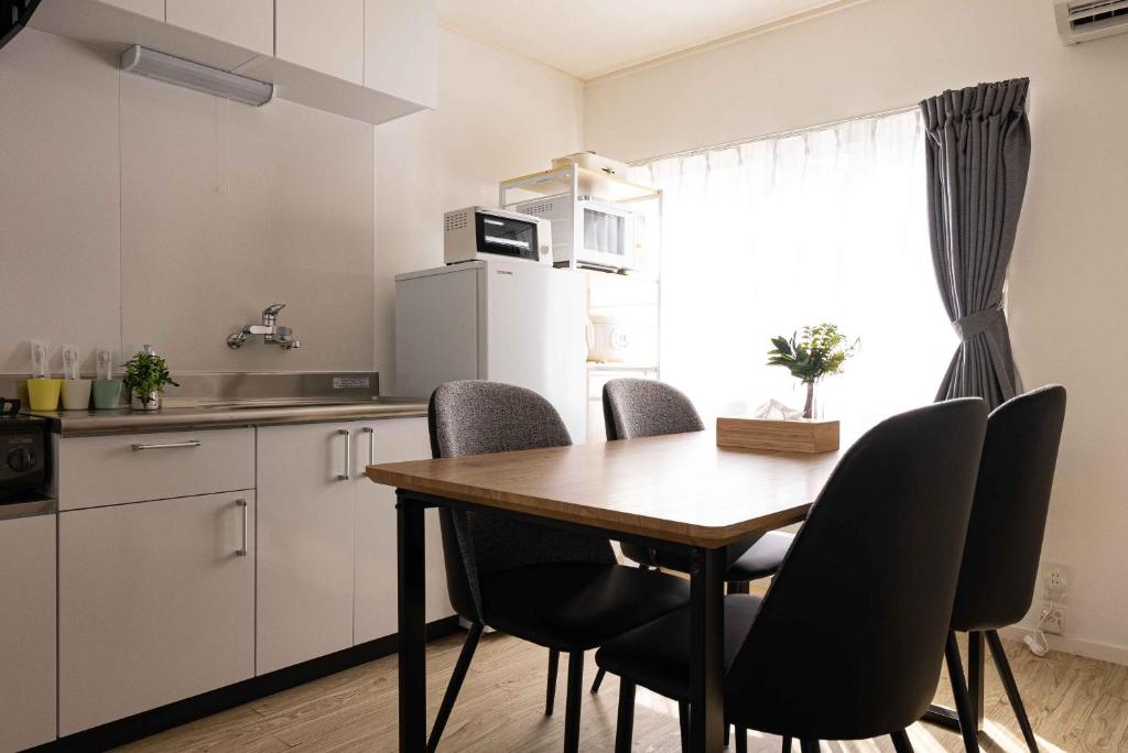 a kitchen with a wooden table and black chairs at Lino下伊福 in Okayama