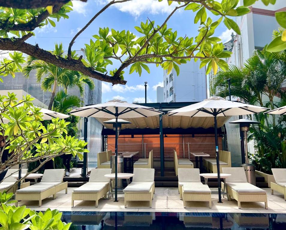 a poolside patio with tables and chairs and umbrellas at Hotel Palm Royal Resort Kokusai Street in Naha