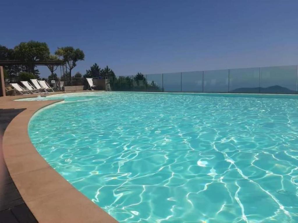 a large swimming pool with blue water at Appartement Magliolo Ligurie / Piscine - SPA - Vue in Magliolo