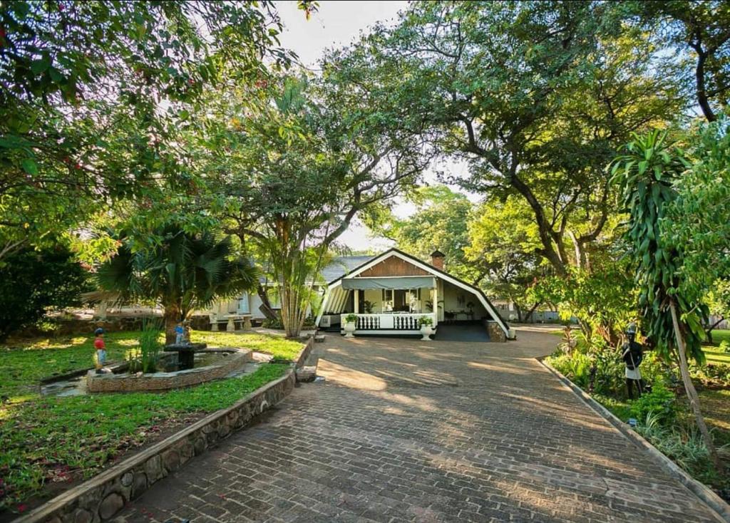 a house with a brick driveway in front of a yard at A wonderful 5 bedroomed 4 bathroom Villa with swimming pool gym garden of the highest quality - 2215 in Victoria Falls