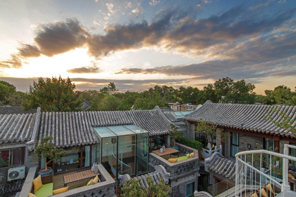 uma vista aérea dos telhados das casas com o pôr-do-sol em Beijing Le Zai Nan Luo Gu Xiang Wang Fu Jing Forbidden City Courtyard Hotel em Pequim