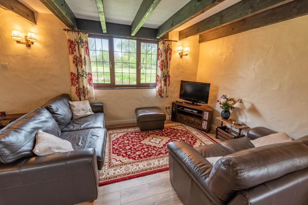 a living room with two leather couches and a television at Lakeside Cottage in Woolacombe