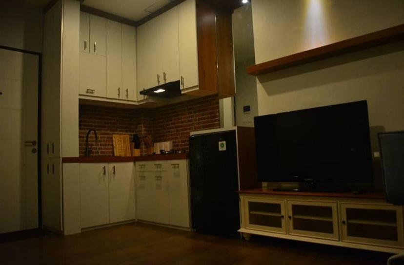 uma cozinha com uma televisão de ecrã plano numa bancada em Syndicet Apartemen em Wirolegi
