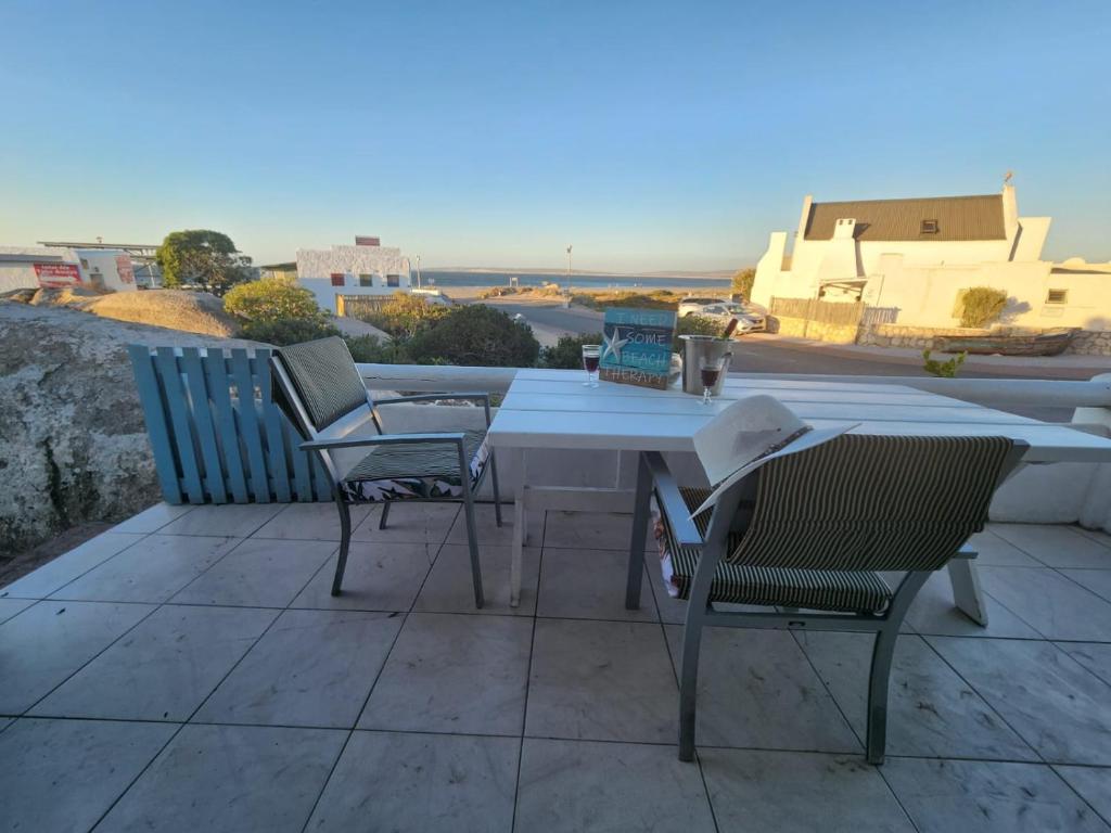 a table and chairs on a patio with a view of the ocean at Duintjie Beach Cottage in Paternoster