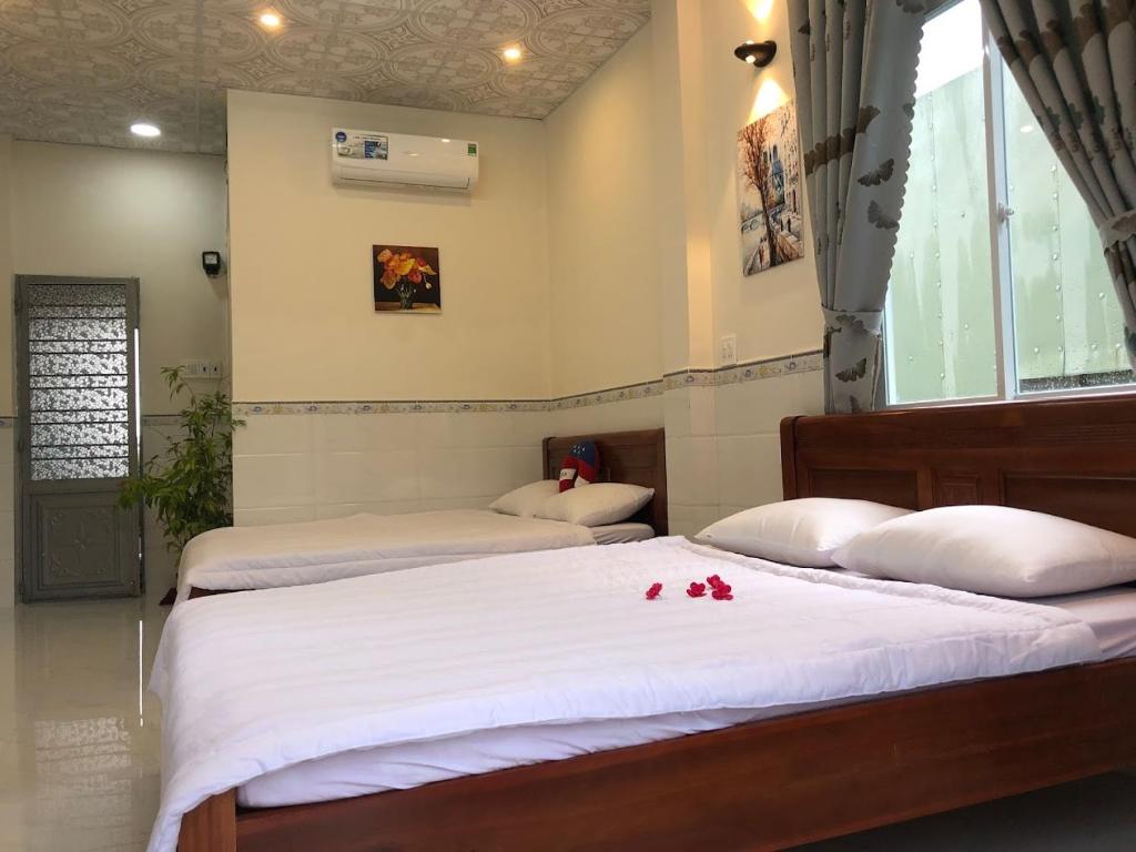 2 camas en una habitación con flores en la cama en Sunny Homestay Quy Nhơn en Quy Nhon
