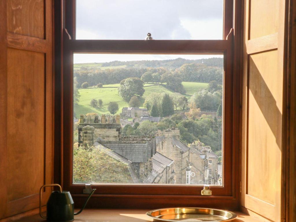 a window with a view of a village through it at Chews Cottage in Pateley Bridge