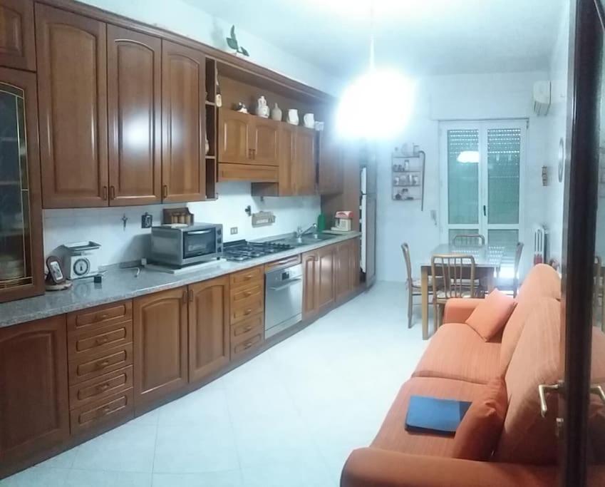 a kitchen with wooden cabinets and a couch in a room at Appartamento 3 letti con cucina e parcheggio privato gratuito in Candela
