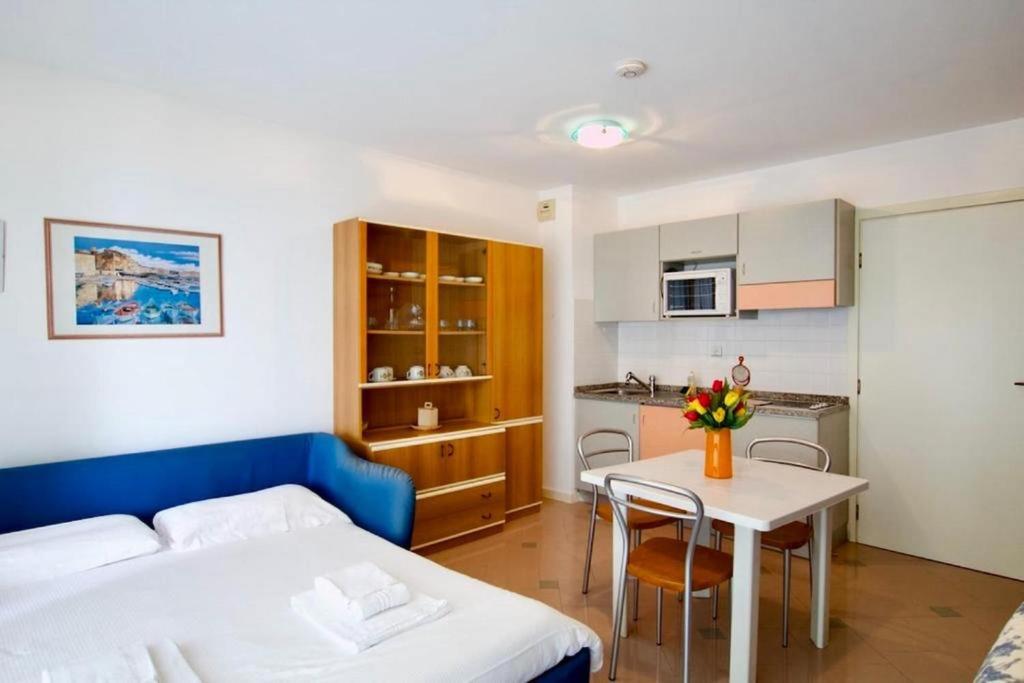 ein Schlafzimmer mit einem Bett und einem Tisch sowie eine Küche in der Unterkunft Monte Carlo Terrace, frontière Monegasque appartement vue mer in Beausoleil