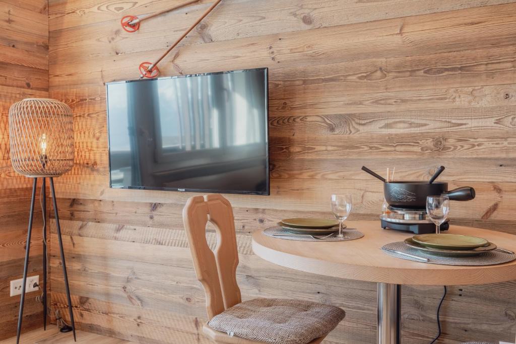 d'une salle à manger avec une table et une télévision murale. dans l'établissement Charmant studio avec une vue imprenable, à Nendaz