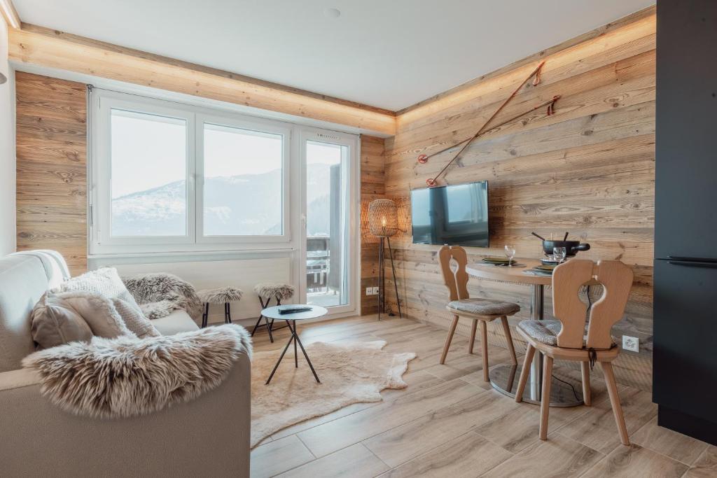 - un salon avec des murs en bois, une table et des chaises dans l'établissement Charmant studio avec une vue imprenable, à Nendaz