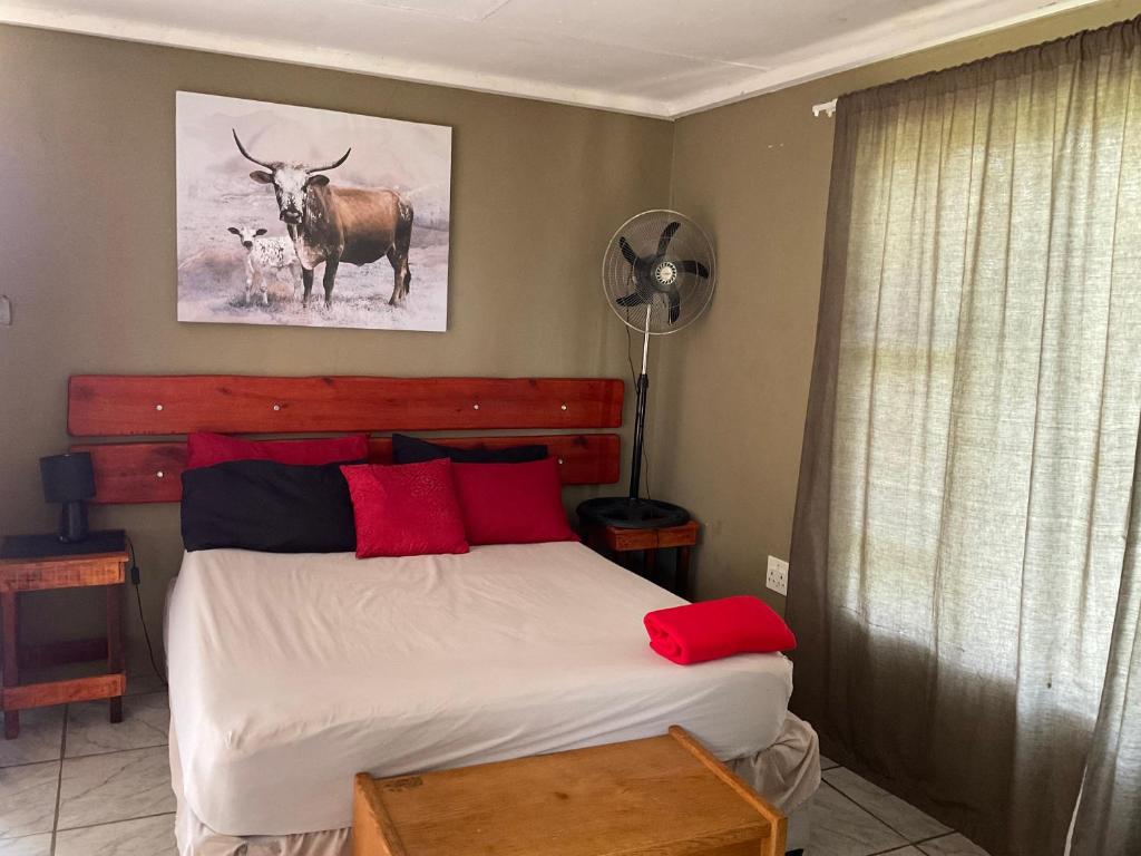 una camera da letto con un letto con cuscini rossi e un disegno di cervo di Letaba Waterfront Lodge a Letaba Wildlife Reserve