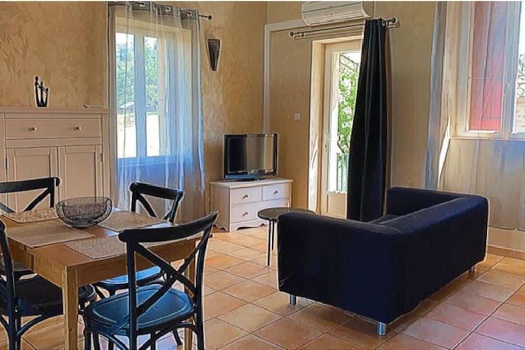 ein Wohnzimmer mit einem Tisch und Stühlen sowie einem TV in der Unterkunft Le Mas Gabantelye in Saint-Paulet-de-Caisson