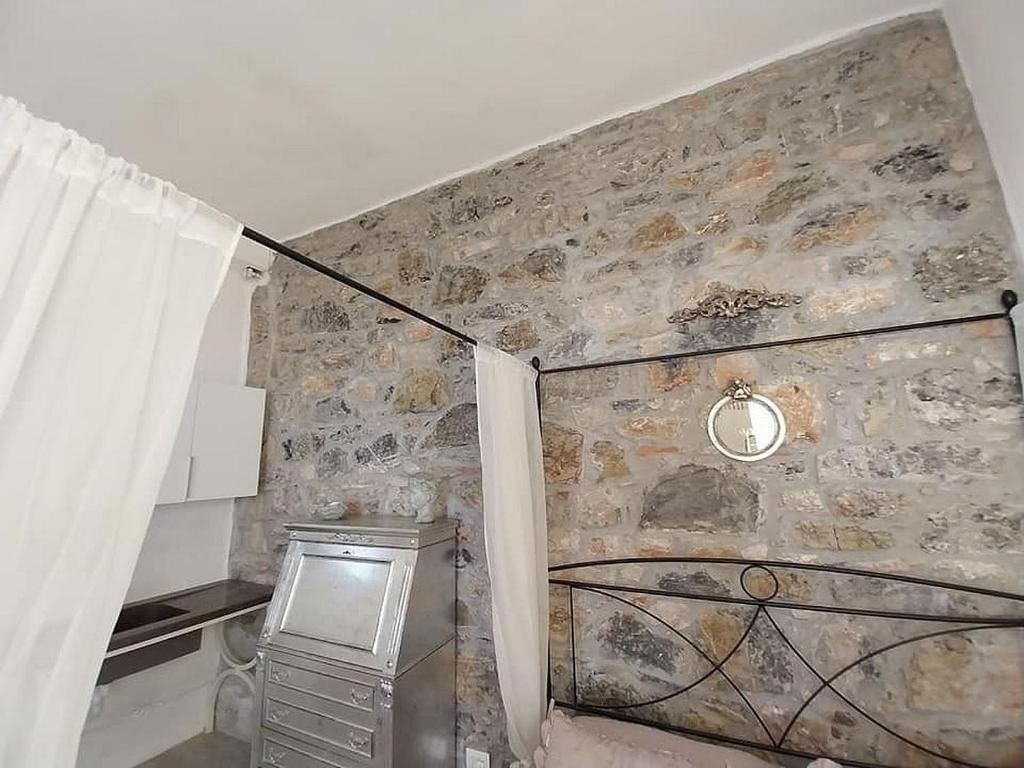 Pokój z kamienną ścianą z oknem i zasłoną w obiekcie Monolocale con bagno, angolo cottura e letto matrimoniale a Baldacchino w mieście Monterotondo