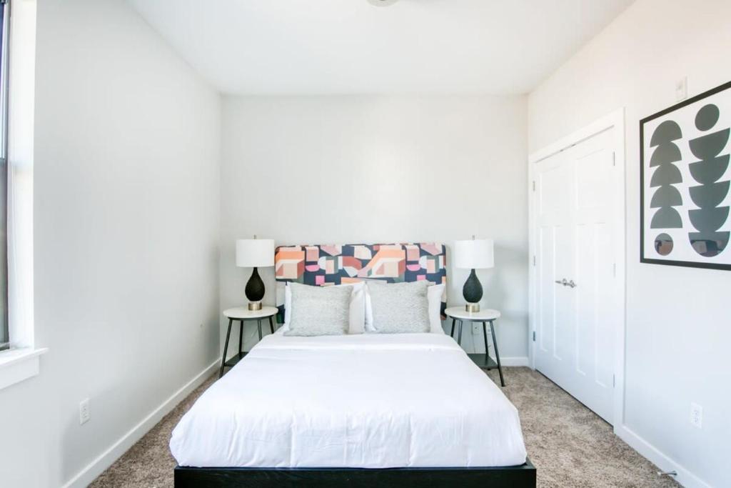 a white bedroom with a bed and two lamps at CozySuites Music Row Chic 1BR w free parking 57 in Nashville