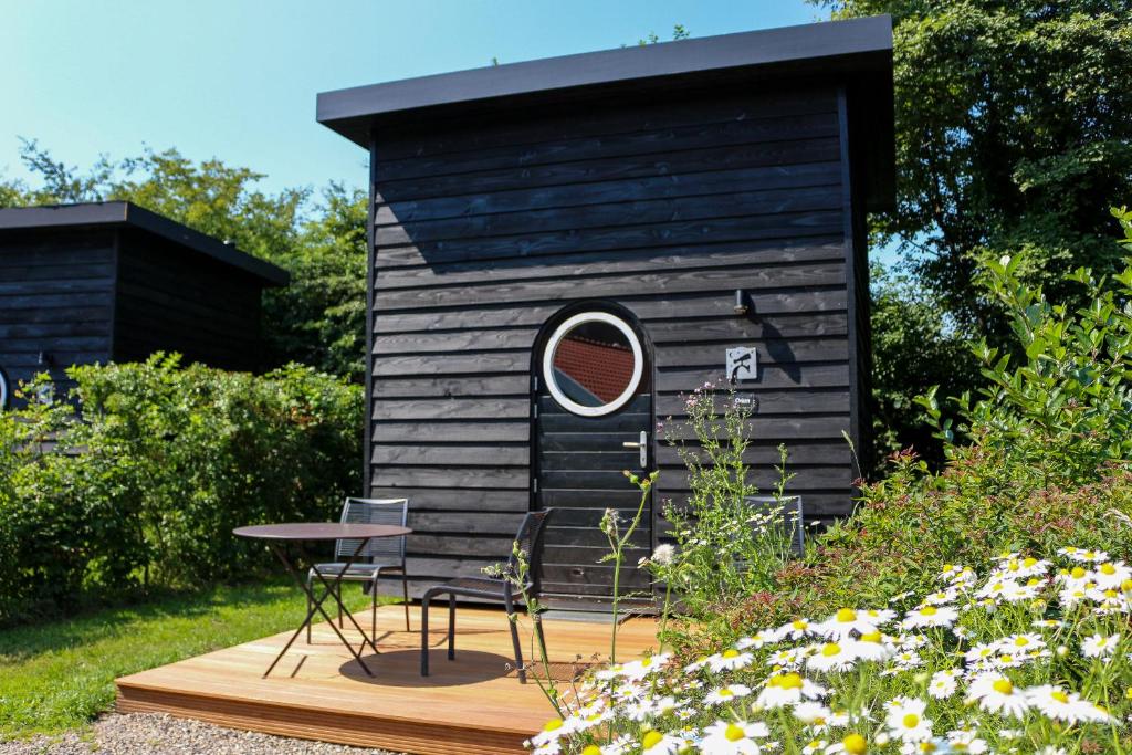 - un petit bâtiment noir avec une table et un miroir dans l'établissement Sterrenkubus, à Lattrop