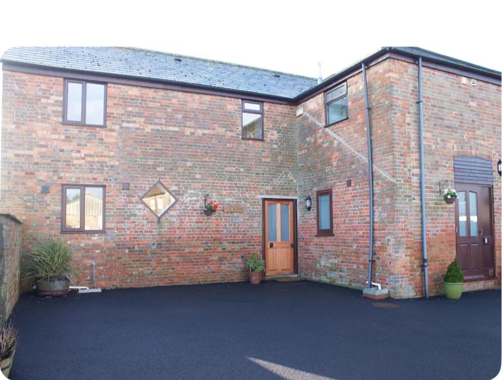 una casa de ladrillo con una entrada delante de ella en The Old Barn - Bramble Farm Cottages en Ferndown