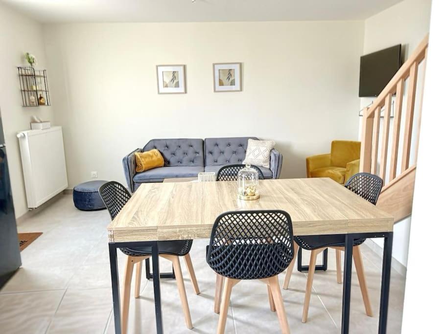 uma mesa e cadeiras numa sala de estar com um sofá em Le Gîte de la Forêt - Montmacq em Thourotte