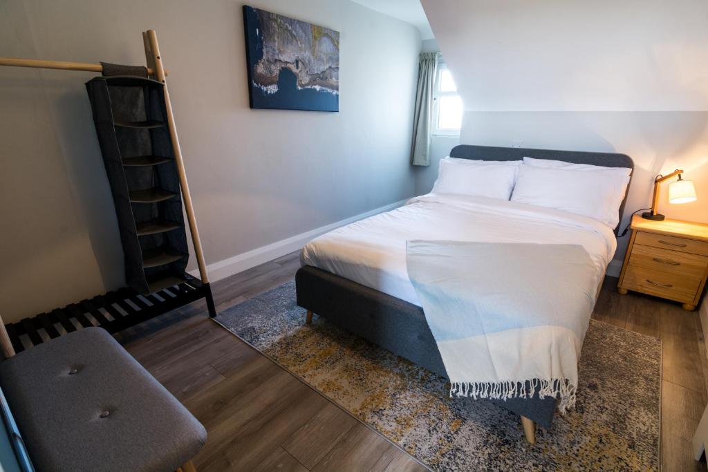 a bedroom with a bed with white sheets and a ladder at Port Aran House in Kilronan