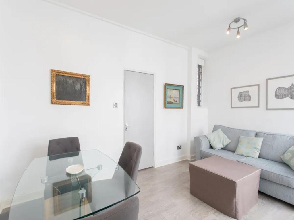 ein Wohnzimmer mit einem Glastisch und einem Sofa in der Unterkunft Paddington Apartment 5mins from St Mary Hospital Pass the Keys in London