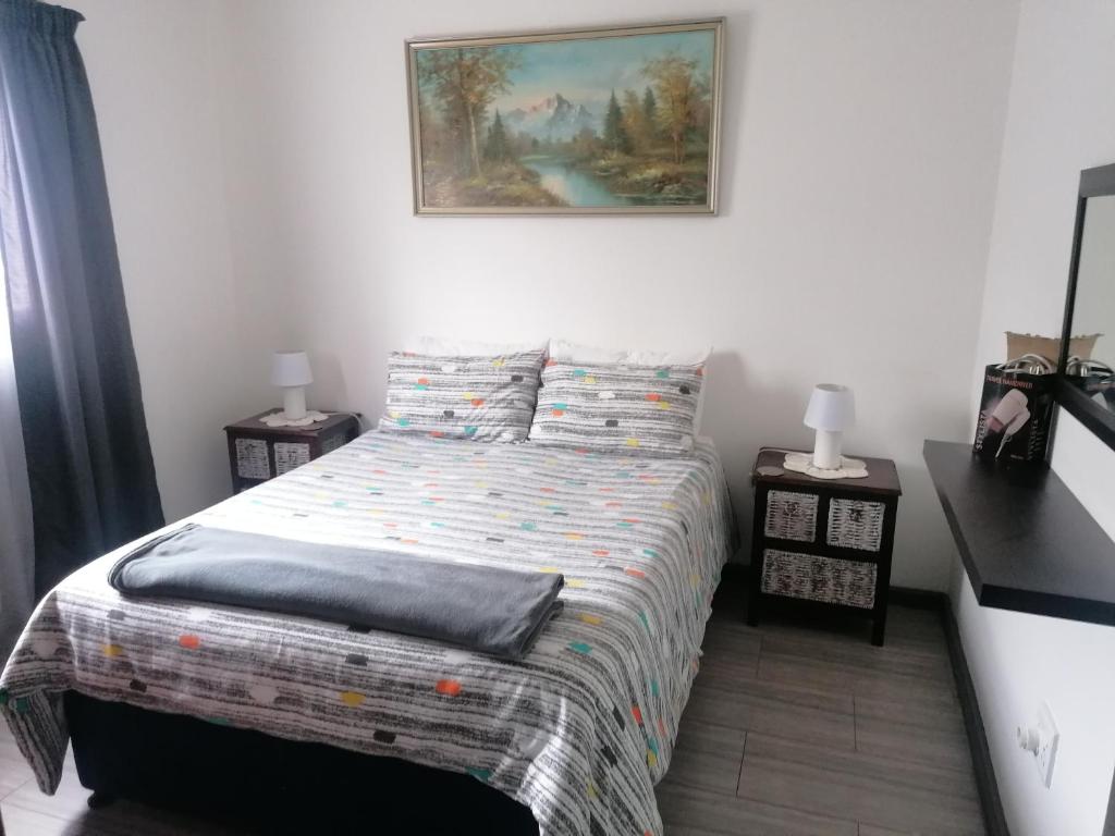 1 dormitorio con 1 cama y una pintura en la pared en Kosies Nest Gastehuis, en Ciudad del Cabo