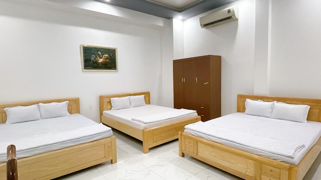 a room with two beds and a cabinet at Nhà Nghỉ Hạnh Phúc in Vị Thanh