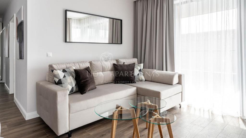 ein Wohnzimmer mit einem Sofa und einem Glastisch in der Unterkunft Lion Apartments - SCALA City Center Apartments&Studio IIA in Danzig