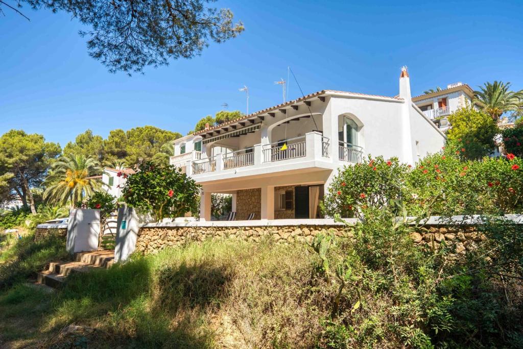 una gran casa blanca en una colina con árboles en Villa Arena, en Es Mercadal